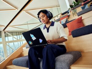 Female developer working on a laptop wearing headphones. programmer; working open space; typing; professional developer; prodev; pro dev; work anywhere;headphones. 