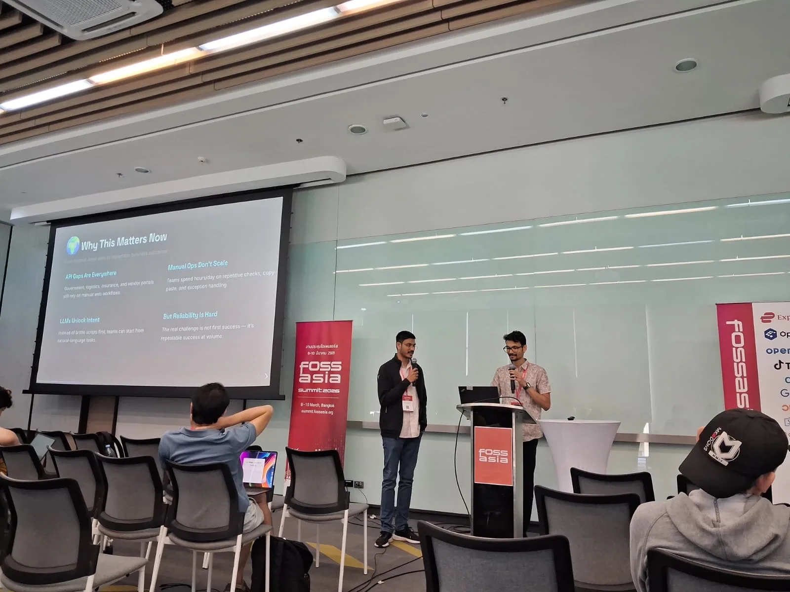 Two speakers presenting a session about APIs, AI, and reliability to attendees at the FOSSASIA Summit conference.