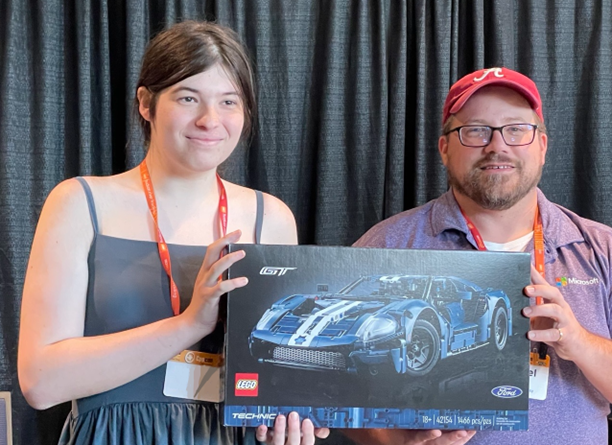 A CppCon attendee holding a LEGO prize next to Microsoft booth staff