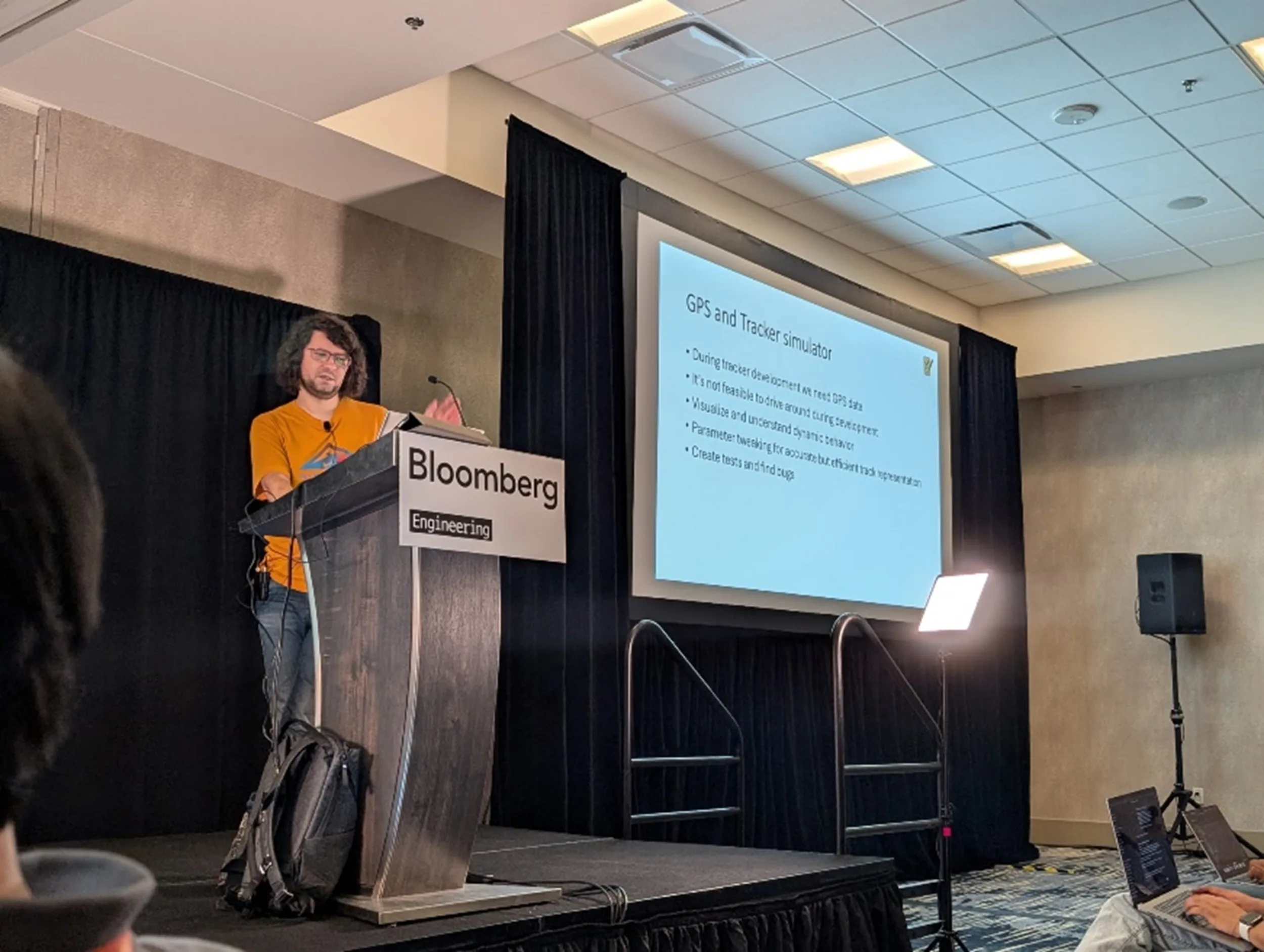 An image of a person standing in front of a projection screen showing a slide from their talk on LLMs and systems programming