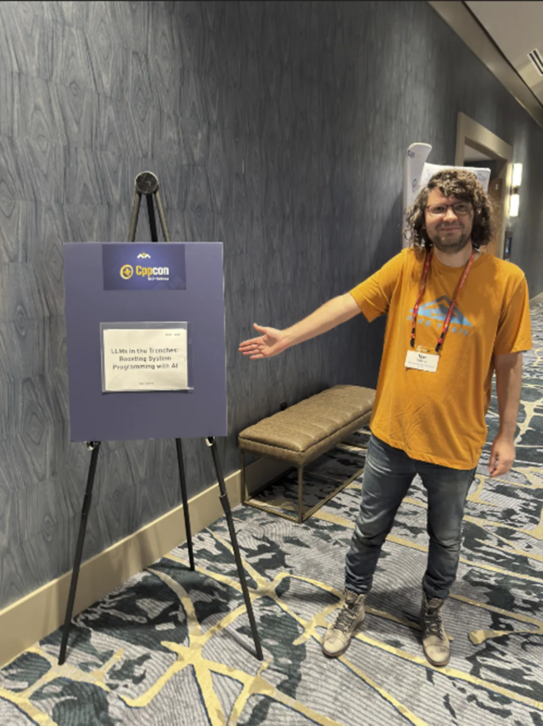 An image of a person standing in front of a CppCon talk session placard showing the title of the talk and the speaker name