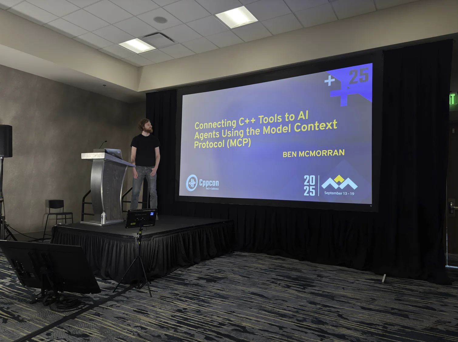 An image of a person standing in front of a projector screen showing the title slide for a talk on Model Context Protocol (MCP)