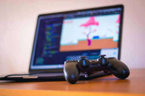 a game controller with a laptop with a game engine in the background