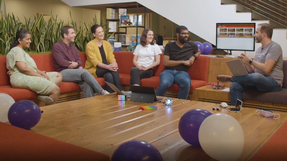 A group of people sitting on a couch with balloons taking part in the Visual Studio keynote.